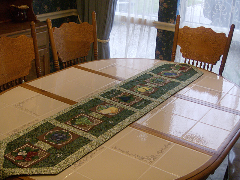 Hand-crafted table runner and matching place mats with various fruit embroidery designs.